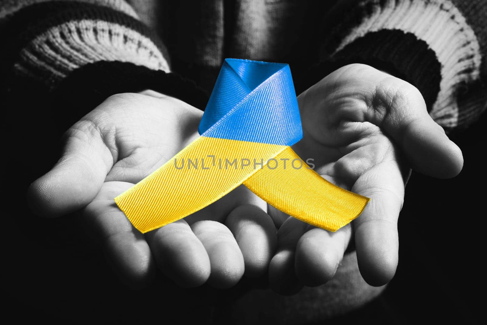 child hands holds yellow blue ukraine ribbon by alexxndr