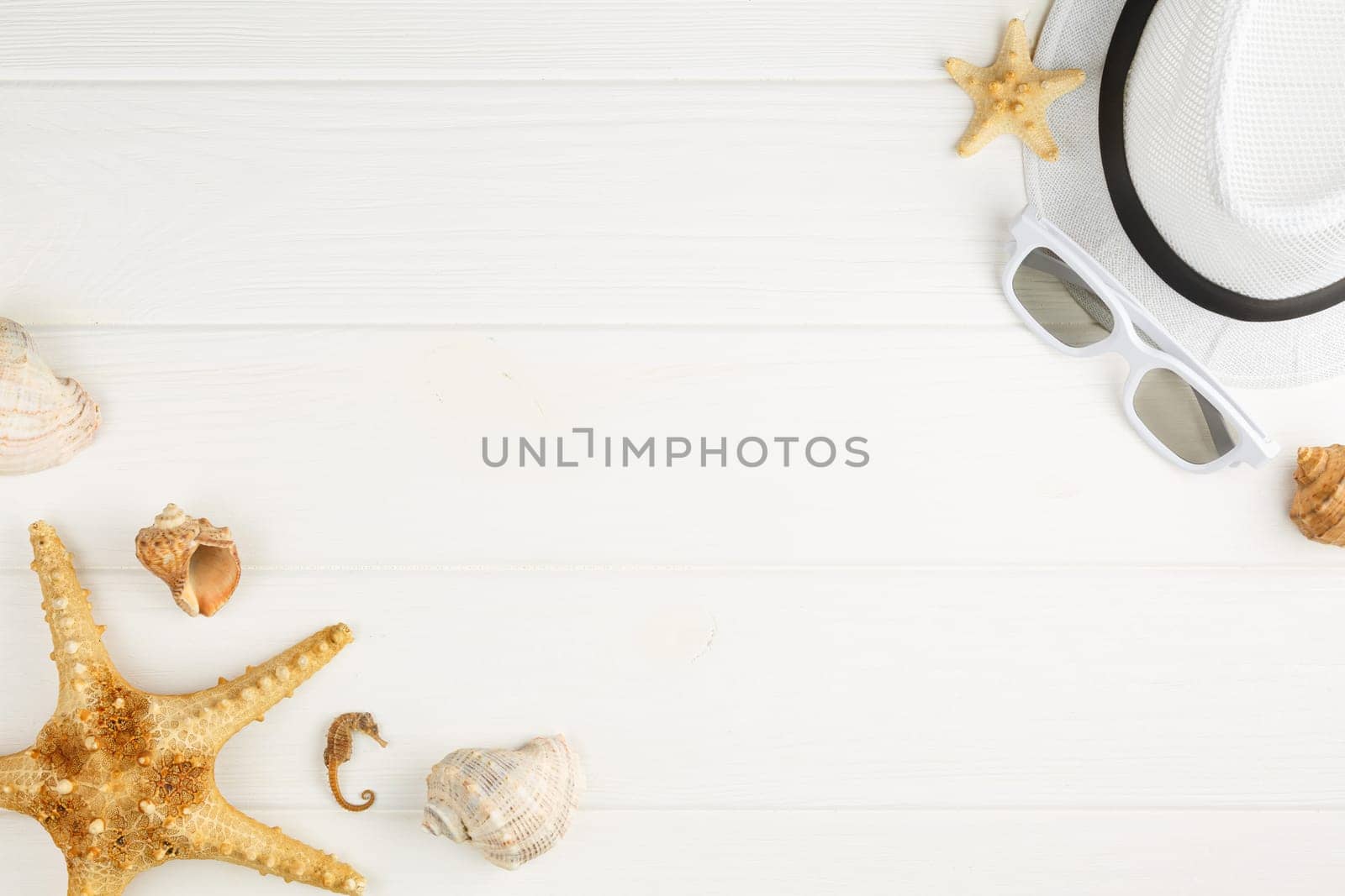 Summer hat with sunglasses on white wooden background. Flat lay. Beach vacation concept. Top view. Starfish and seashells.