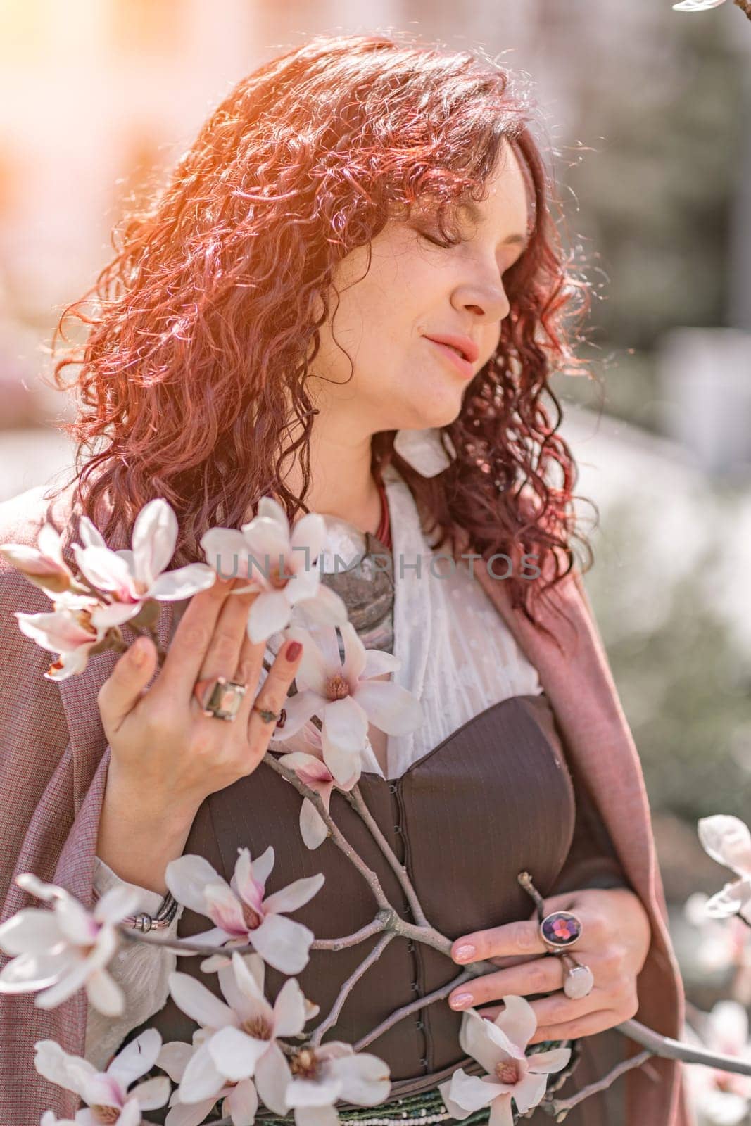 Magnolia park woman. Stylish woman stands near the magnolia bush in the park. Dressed in white corset pants and posing for the camera. by Matiunina