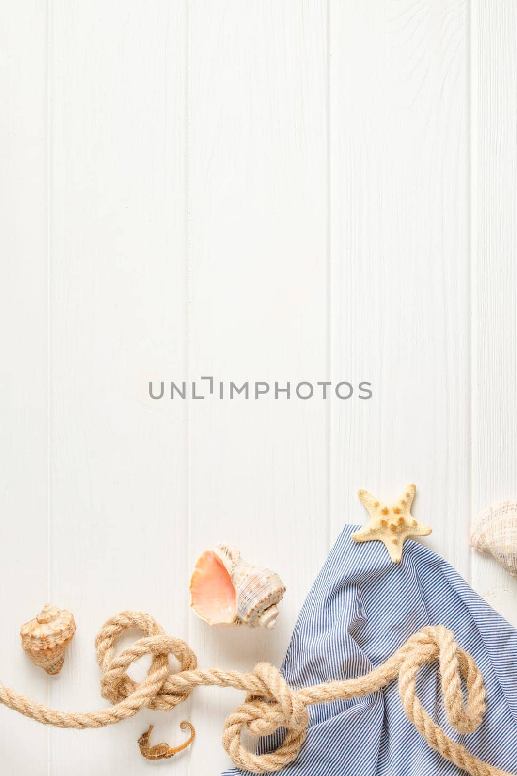 Nautical rope and striped tunic on white wooden background with copy space. Flat lay. Summer vacation concept. Starfish and coral. Top view.