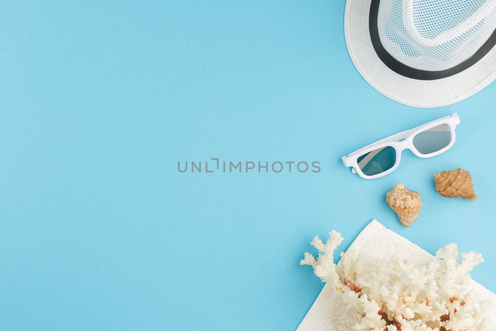 Seashells with corals on a blue isolated background. Top view. Summer vacation concept. Beach hat with sunglasses. Flat lay.
