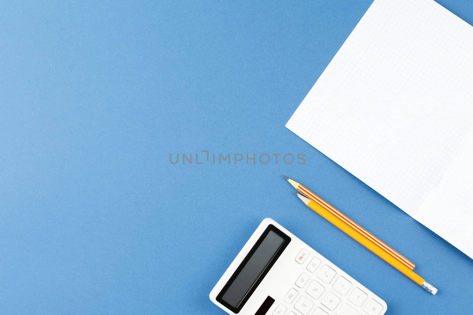 Exercise book with calculator on a blue background. Notebook on the school desk. Back to school concept.