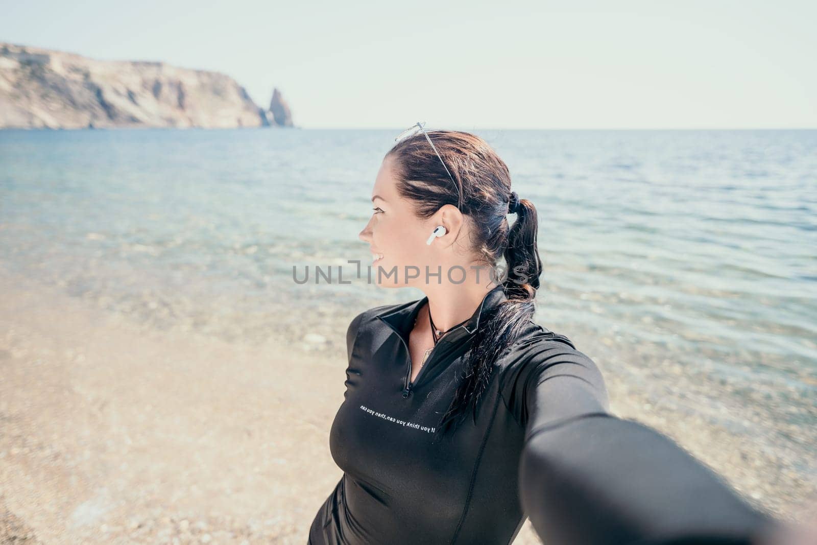 Woman travel sea. Young Happy woman posing on a beach near the sea on background of volcanic rocks, like in Iceland, sharing travel adventure journey