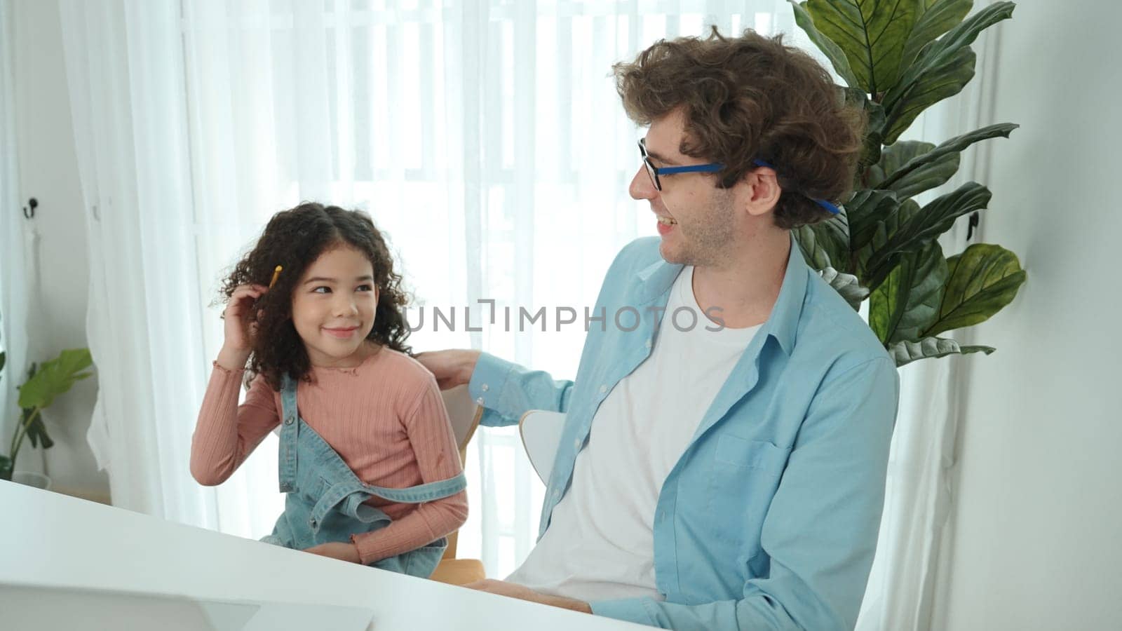 Caucasian father put on pencil on ear while daughter looking at dad and put pencil on ear. Smart dad writing engineering code and generated AI by using laptop. Family spend time together. Pedagogy.