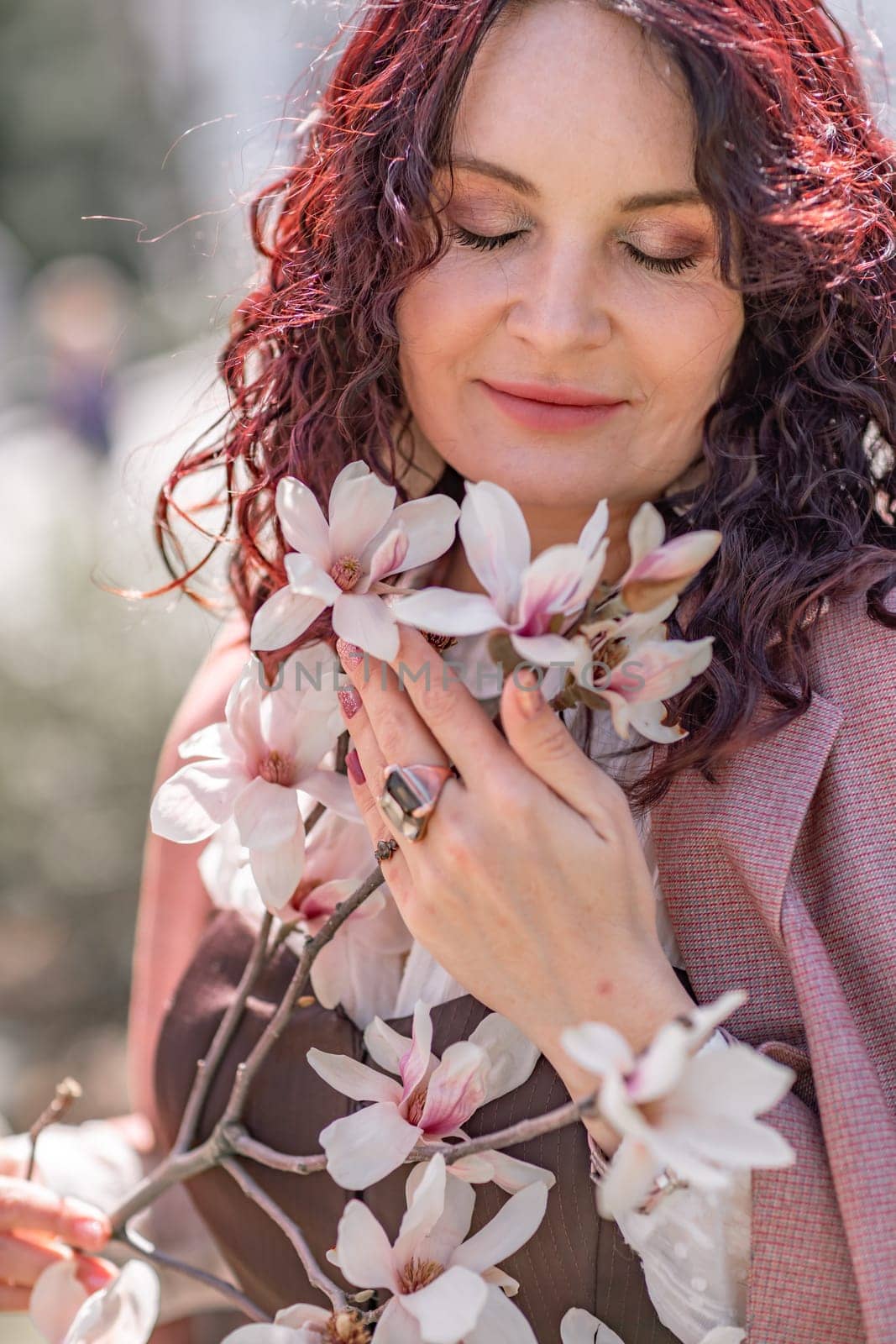 Magnolia park woman. Stylish woman stands near the magnolia bush in the park. Dressed in white corset pants and posing for the camera. by Matiunina