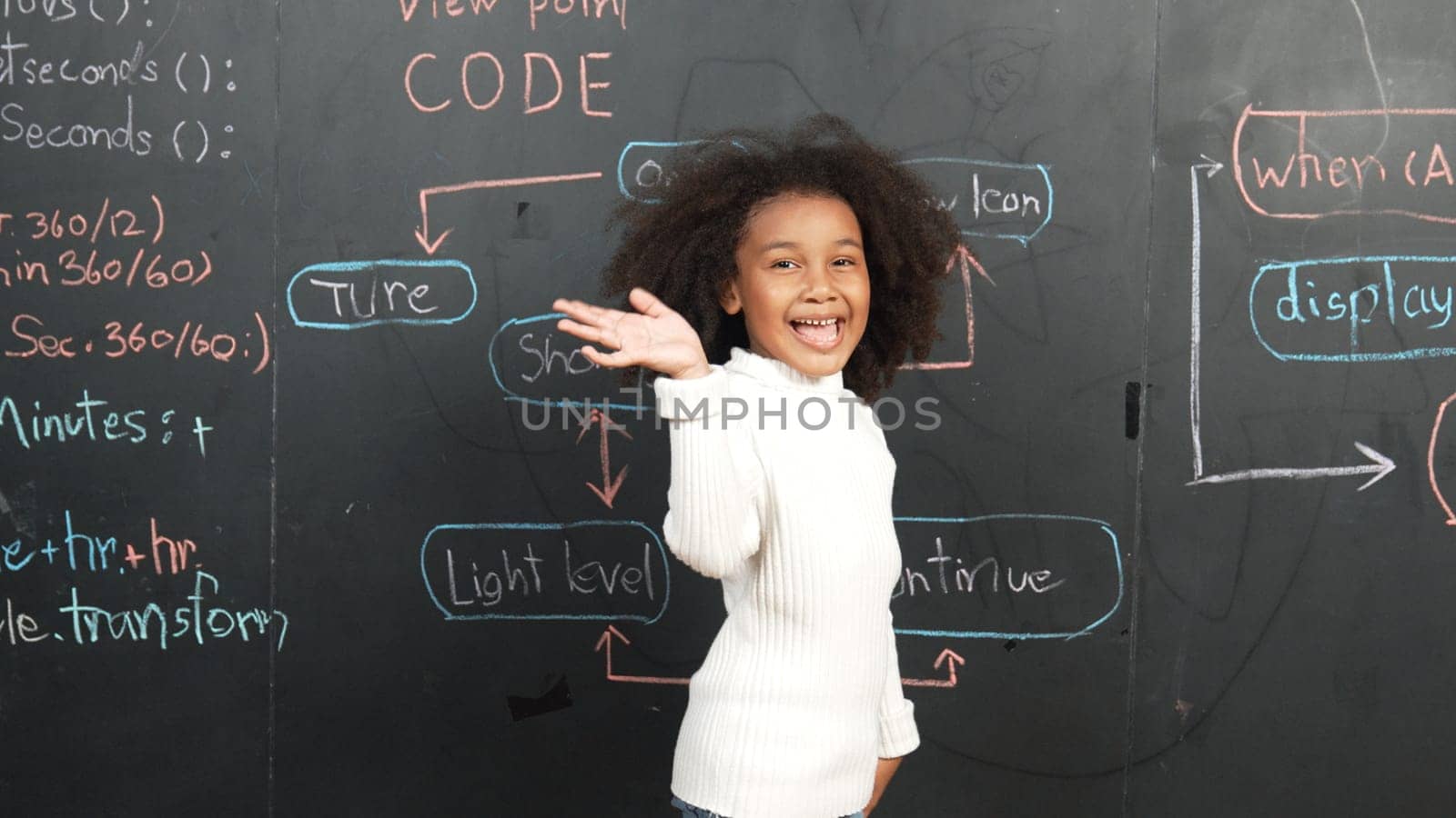 Happy african girl writing blackboard and turnaround to waving at camera while standing at board with engineering prompt or coding, programing system written in STEM technology classroom. Erudition.