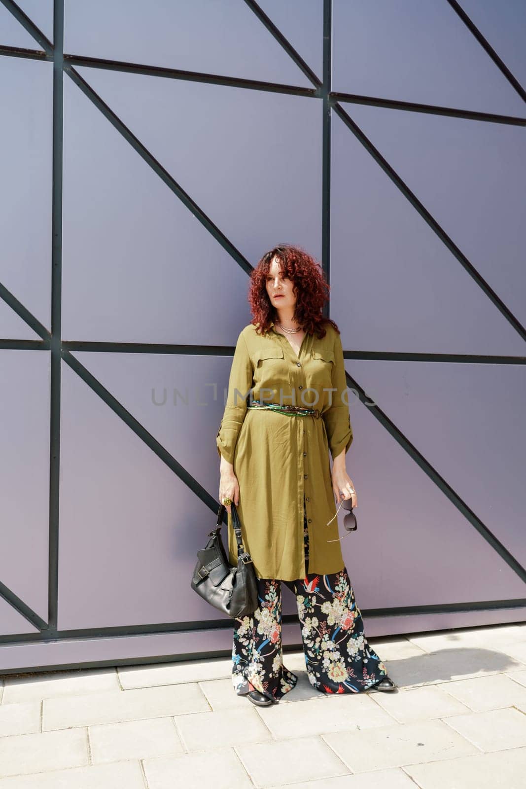 Portrait of a woman standing near a supermarket building. Caucasian model with long brunette hair, wears sunglasses and a khaki dress. by Matiunina