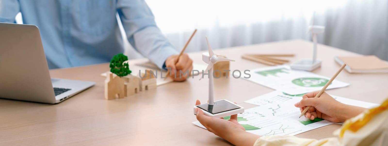 Windmill model was holding by skilled businesswoman while she start represented about benefit of using renewable energy for green business on the meeting table. Closeup. Delineation.