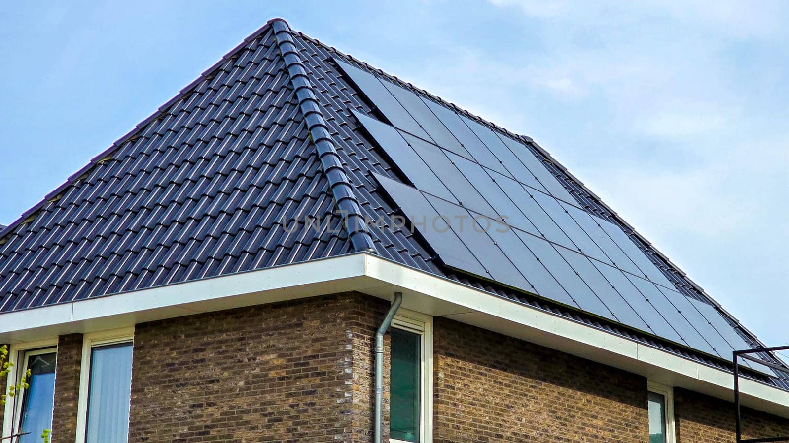Newly built houses with black solar panels on the roof against a sunny sky , new building with black solar panels. Zonnepanelen, Zonne energie, Translation: Solar panel, Sun Energy
