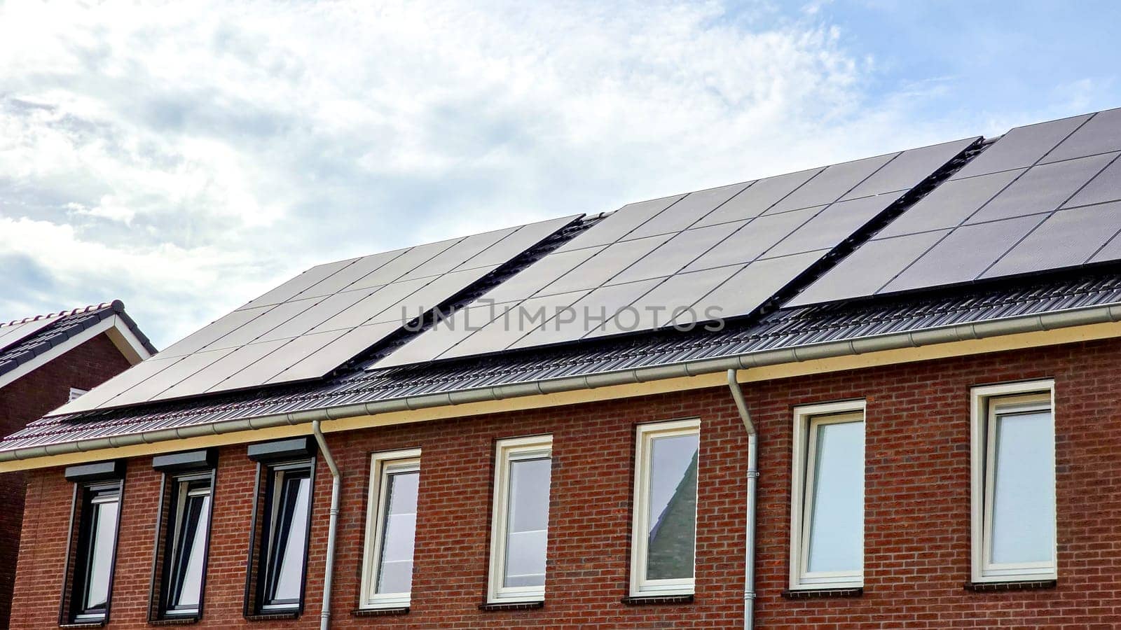 Newly build houses with solar panels attached on the roof against a sunny sky by fokkebok