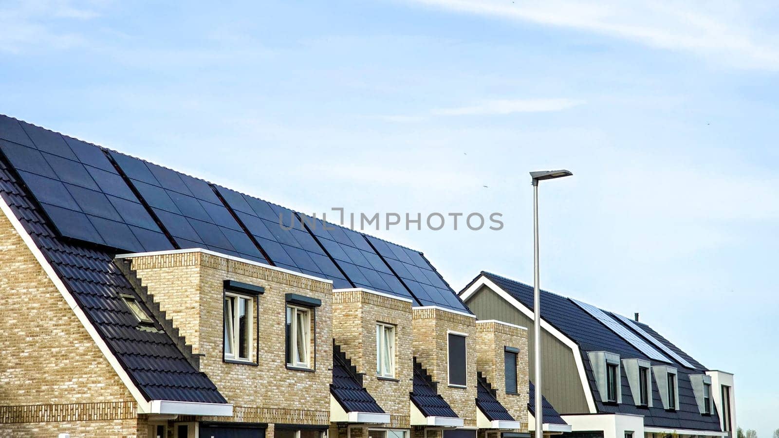 Newly build houses with solar panels attached on the roof against a sunny sky by fokkebok