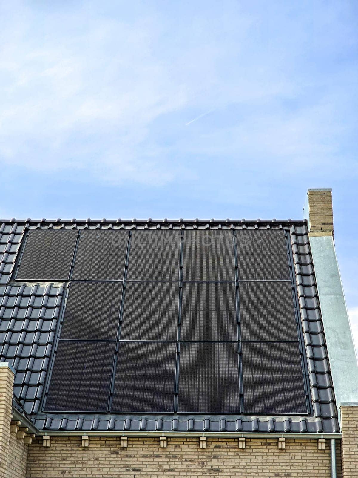 Newly built houses with black solar panels on the roof against a sunny sky Close up of new building with black solar panels. Zonnepanelen, Zonne energie, Translation: Solar panel, Sun Energy