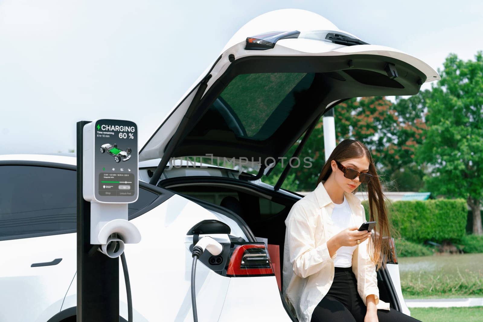 Young woman use smartphone to pay for electricity for EV car. Expedient by biancoblue