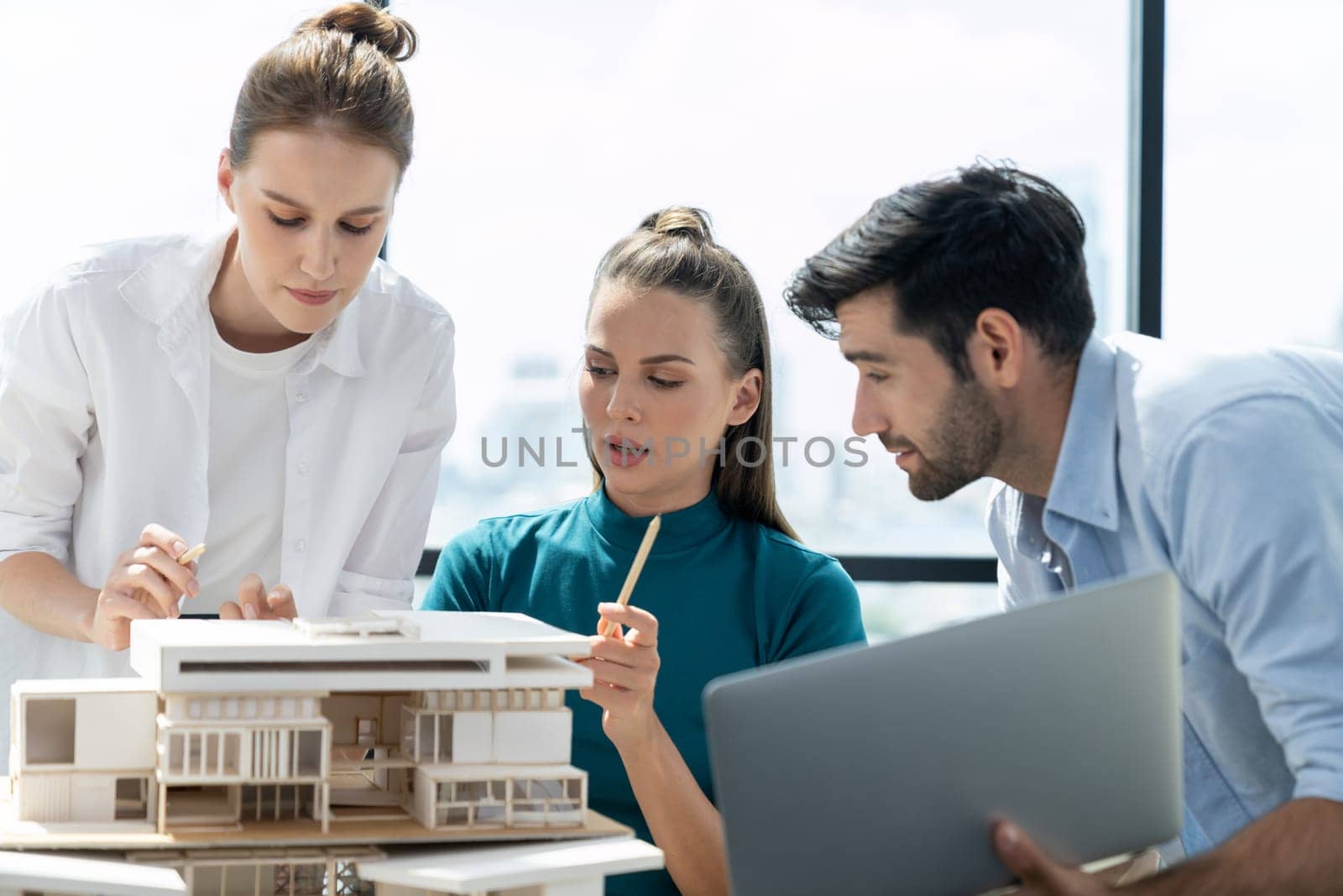 Portrait of skilled architect holding laptop while present idea to engineer team. Group of businesspeople brainstorm and analysis building construction. Civil engineering, working together. Tracery.