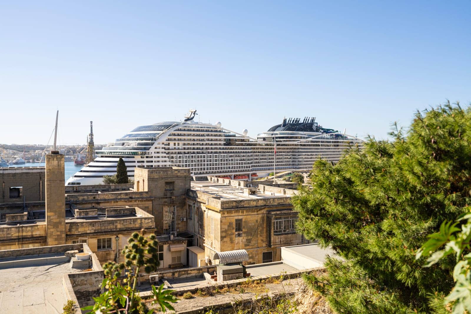Valletta, Malta, April 03, 2024.  a large cruise ship glimpsed in the port from a garden in the city centre