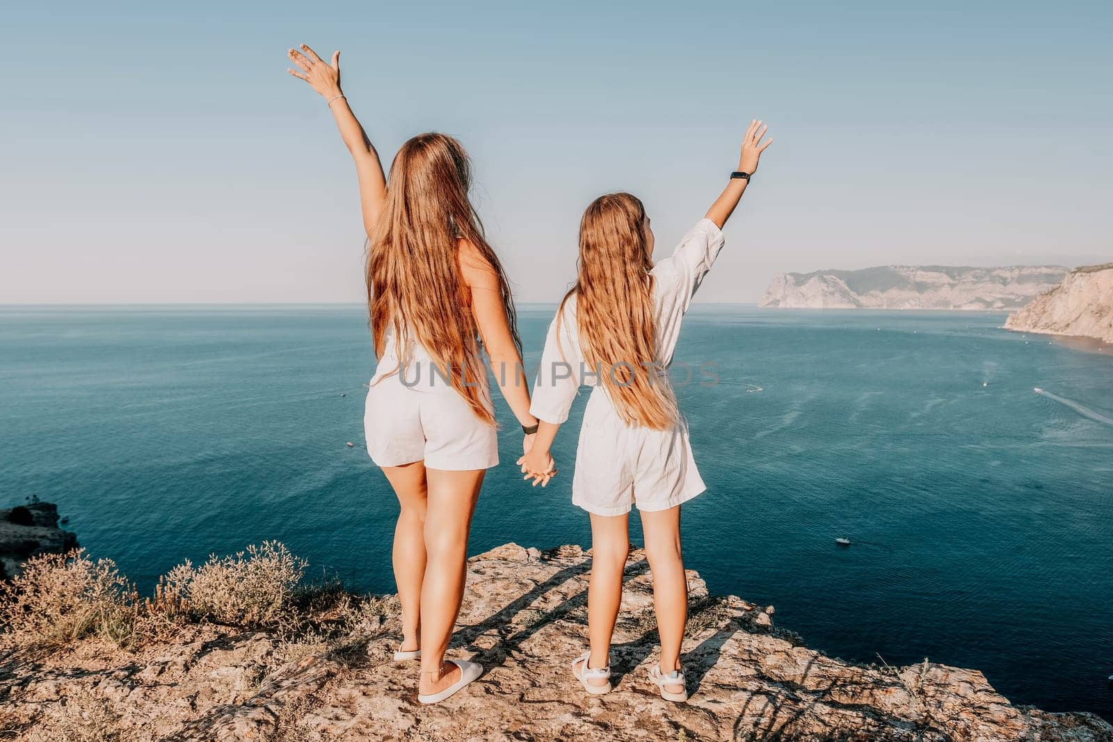 Close up portrait of mom and her teenage daughter hugging and smiling together over sunset sea view. Beautiful woman relaxing with her child.