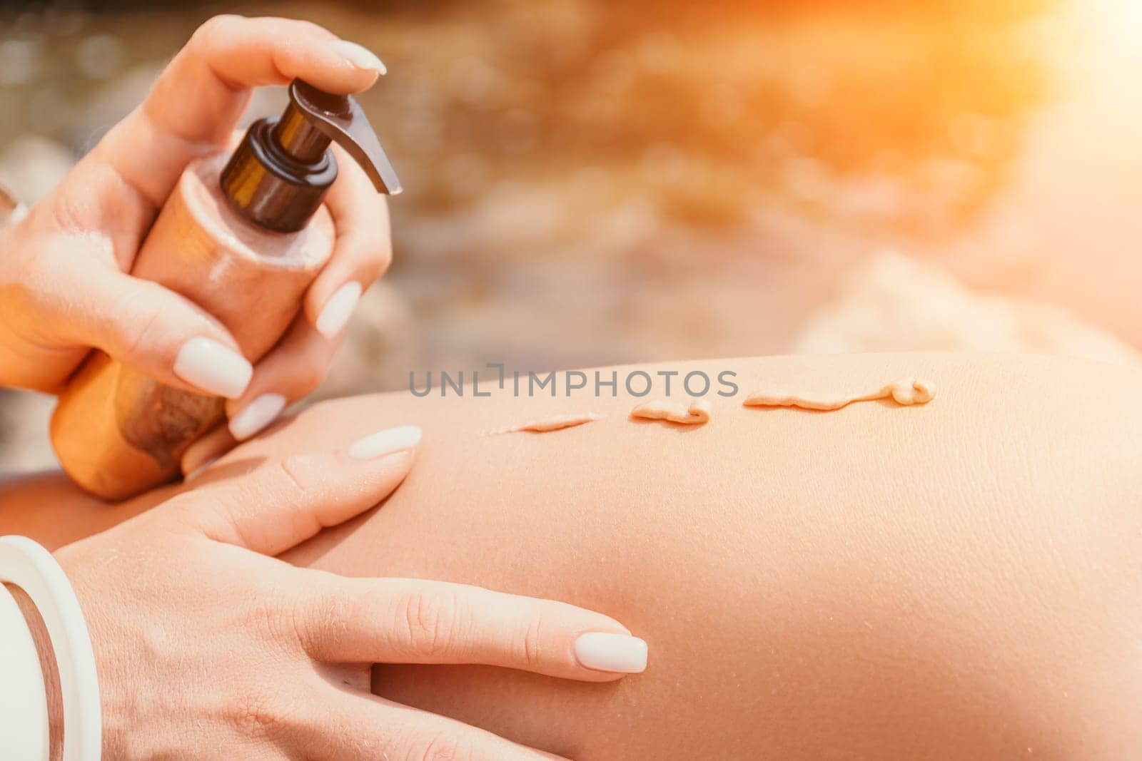 Sexy Woman in bikini apply sun protection cream on her smooth tanned legs. Skin care. Legs on the beach. Portrait of female in hat smearing moisturizing lotion. Sunblock concept.