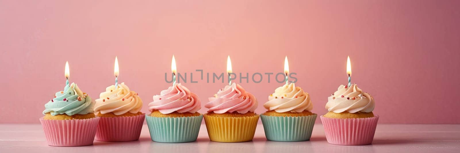 Colorful cupcakes with lit candles are displayed against a pink background, indicating an indoor celebration event marking of joy and celebrating. with free space by Matiunina