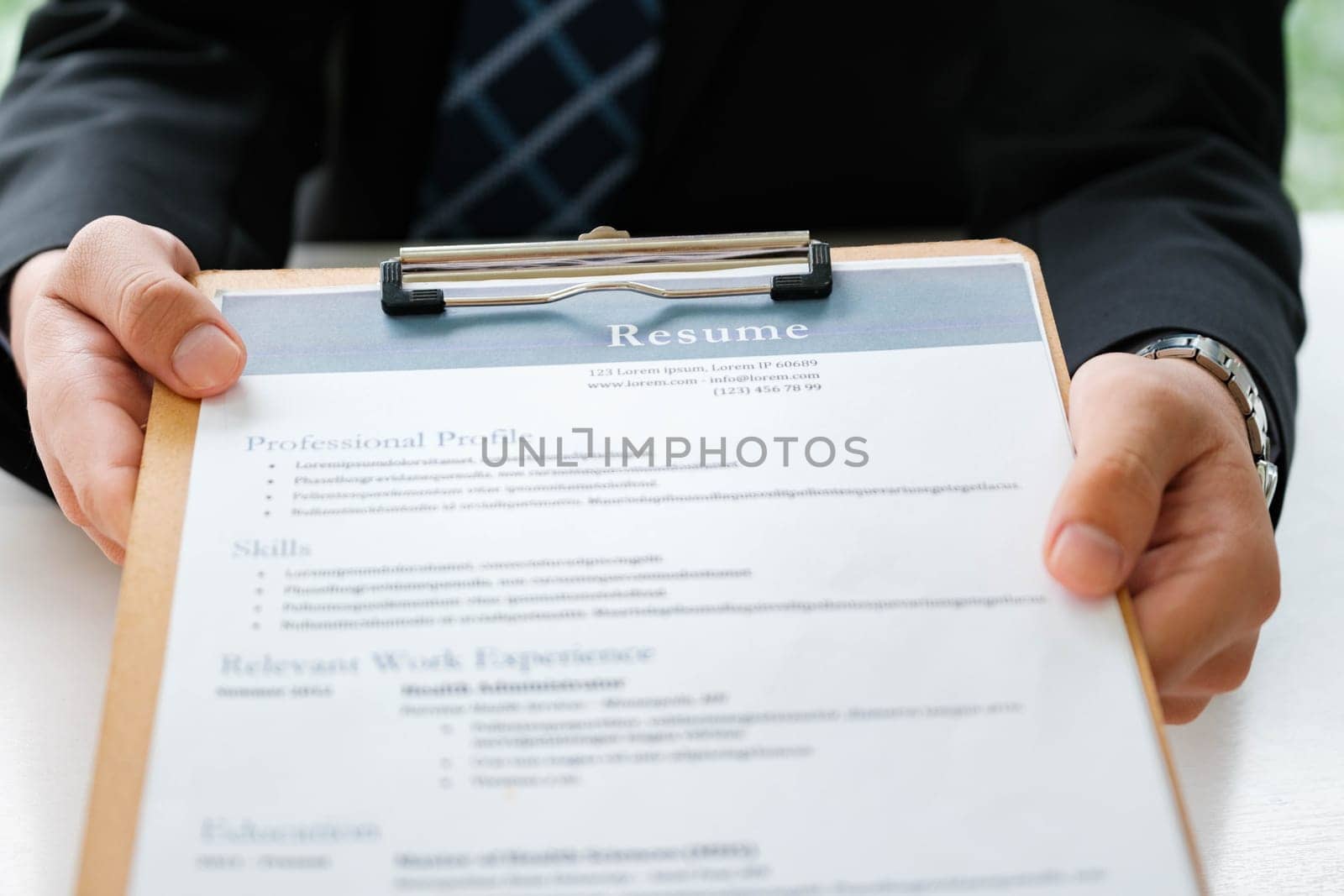 Close-up of a businessman's hands carefully examining a resume, focusing on qualifications for a job candidate.