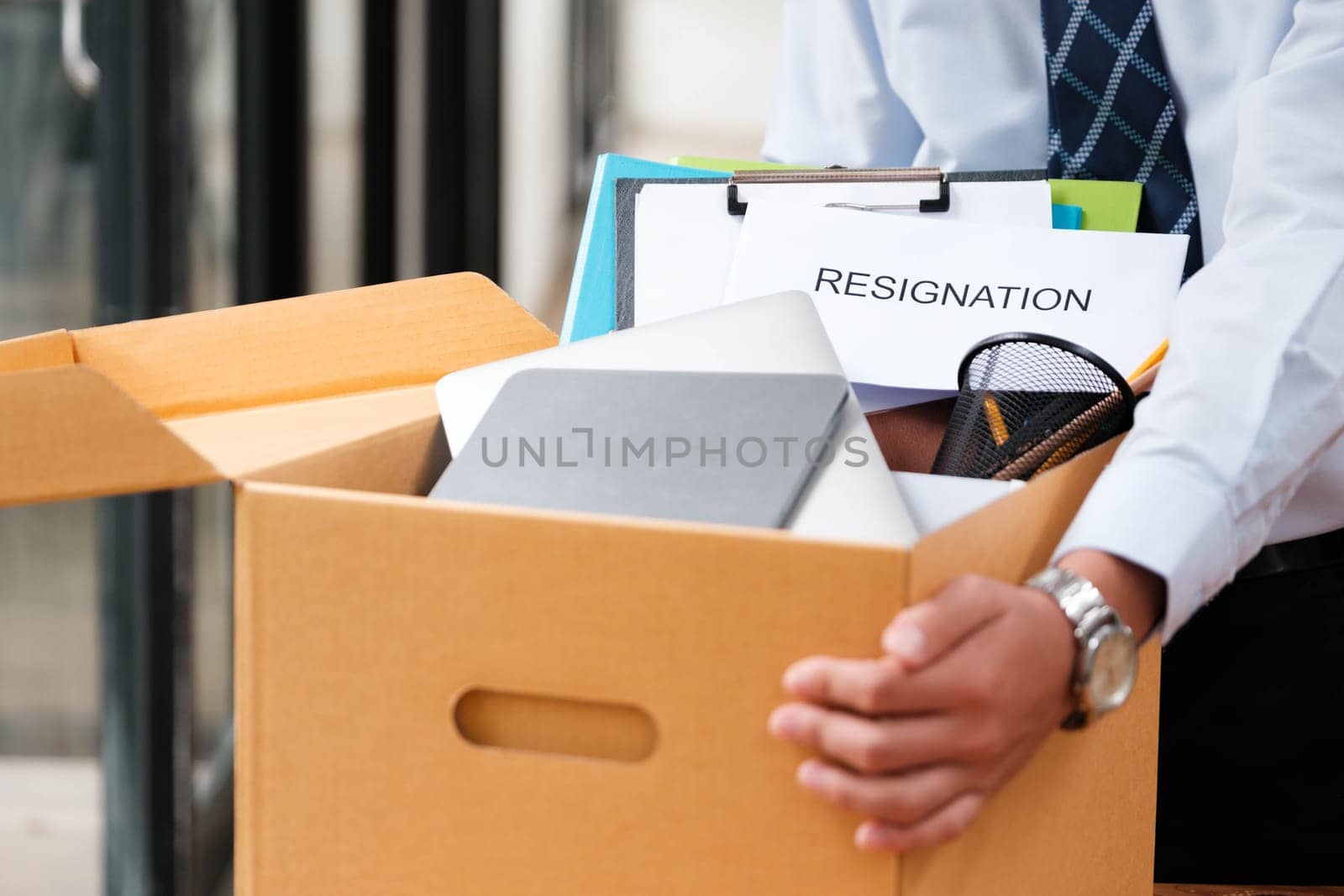 Man places personal items and resignation letter into a box, ending his tenure. by ijeab