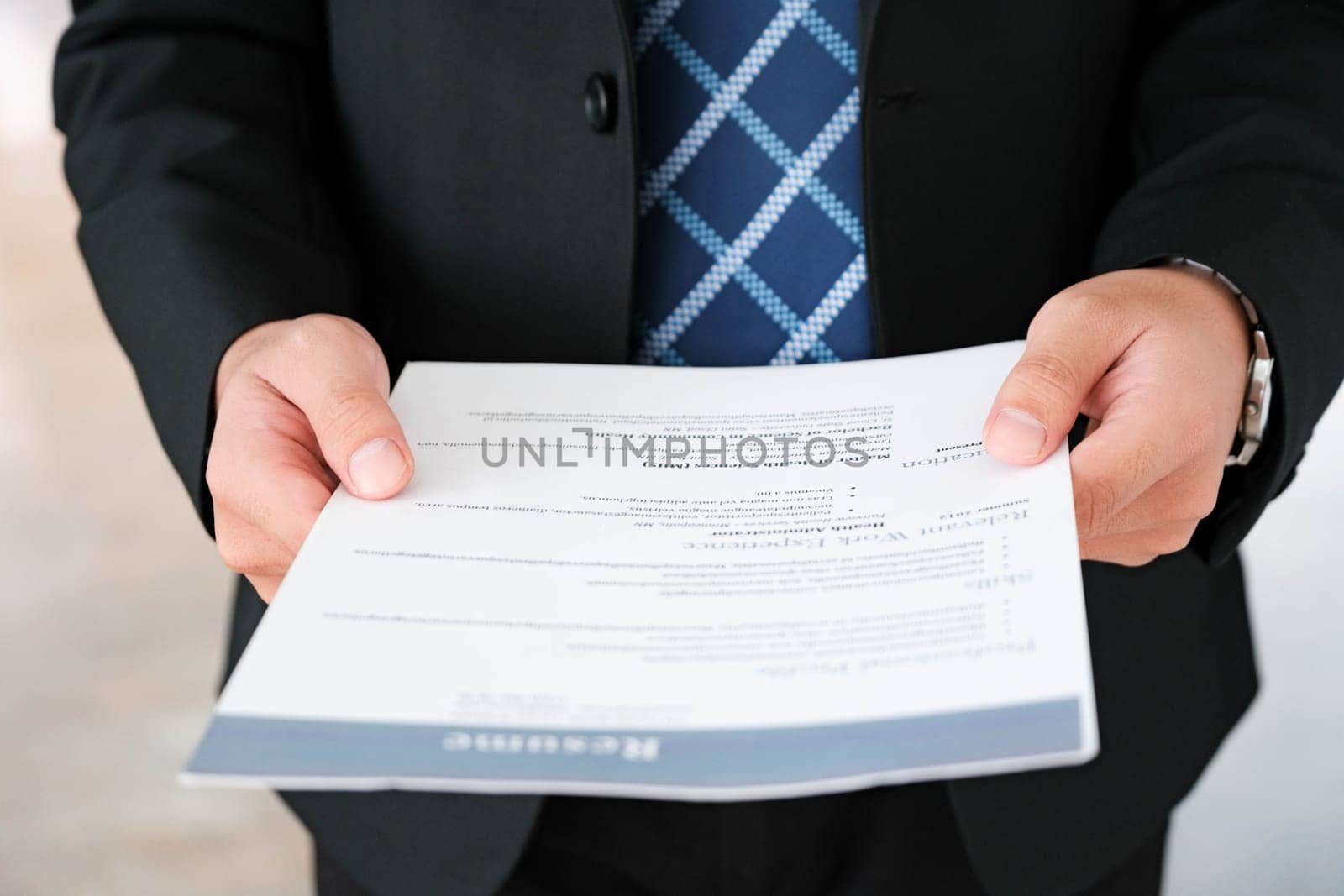 Close-up of a businessman's hands carefully examining a resume, focusing on qualifications for a job candidate.