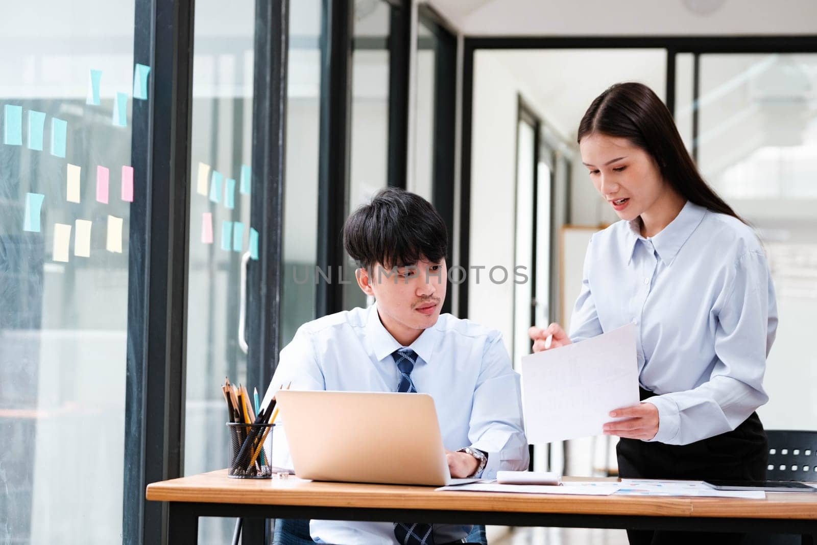 Businesswoman attempting to reason with a stressed colleague showing frustration at a workplace meeting.