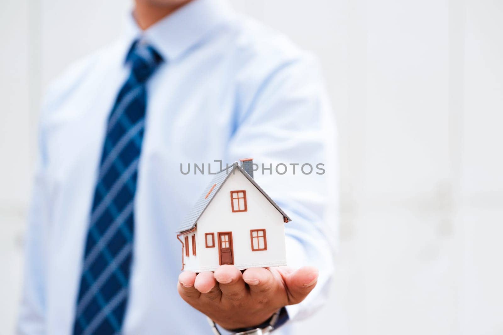 Close-up of real estate agent extending a small house, showcasing property investment. by ijeab