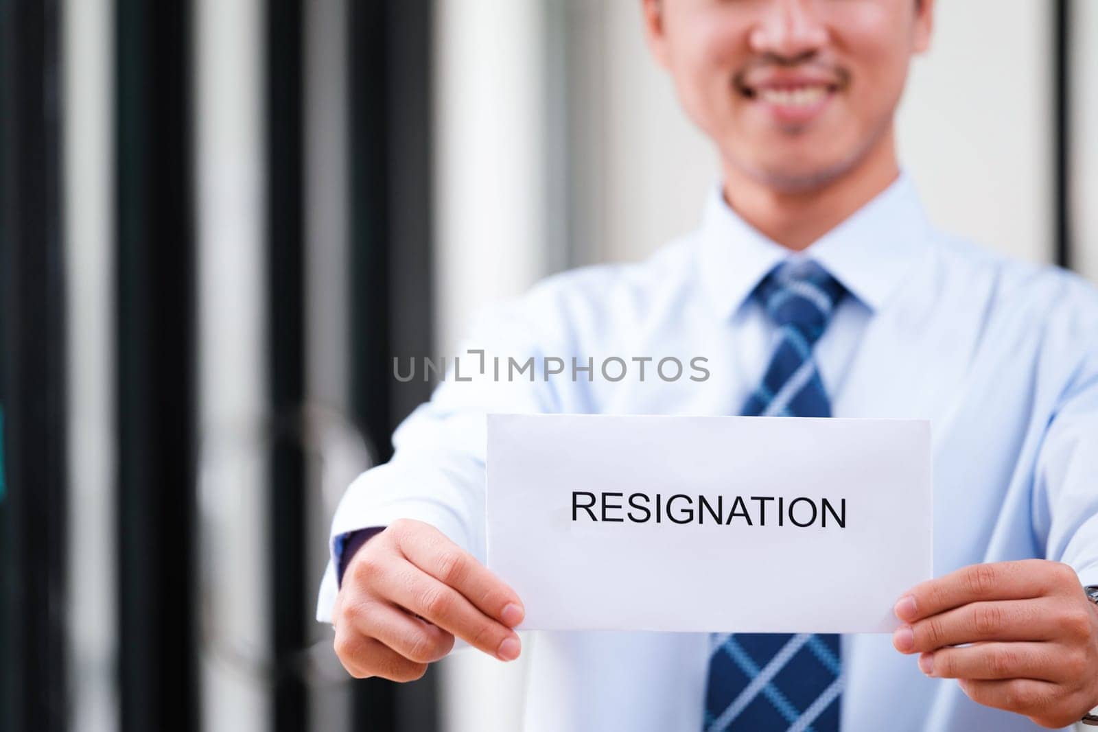 Confident Man Holding Up Resignation Letter with a Smile, Signaling a Positive Transition and Optimistic Outlook on Future Endeavors