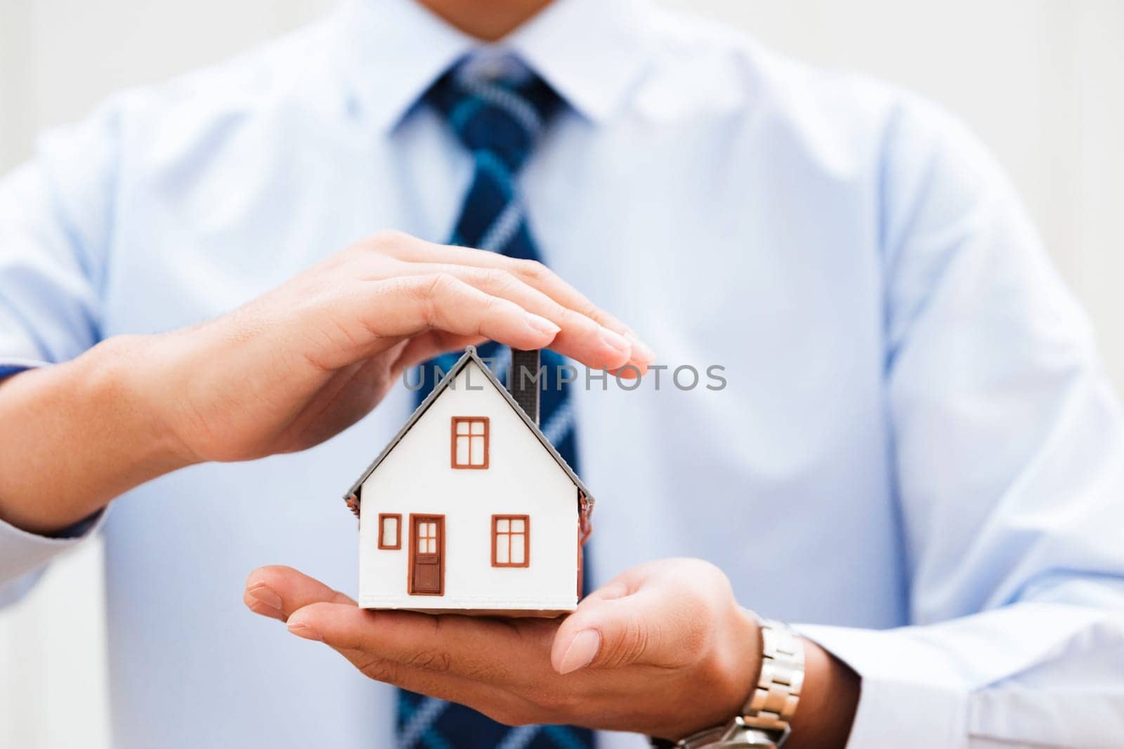 Close-Up of Hands Cradling a Model Home, Symbolizing Protection and Care in Real Estate and Property Insurance Sectors