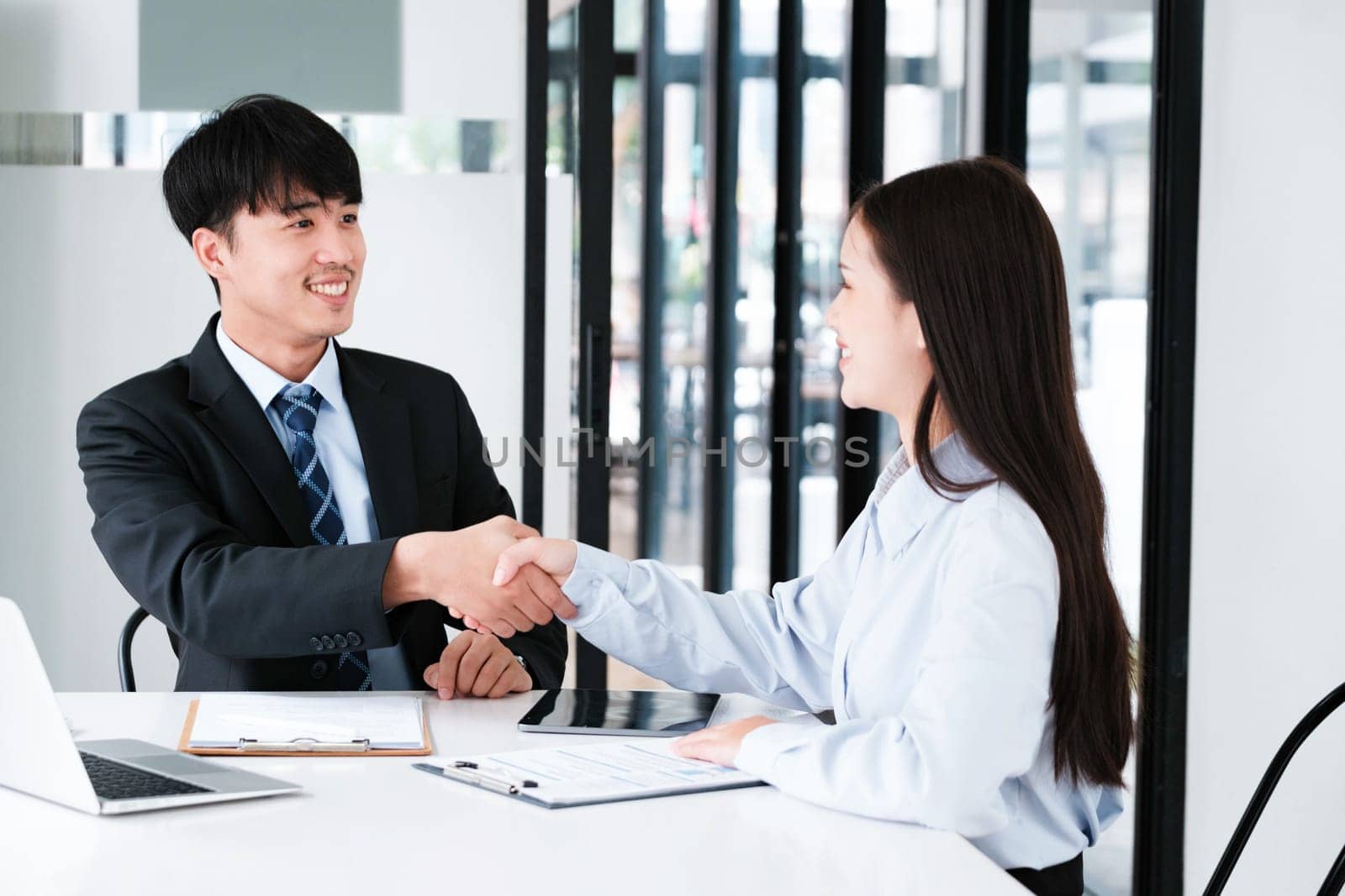 A job interviewer and applicant seal the interview process with a firm handshake, indicating a positive outcome.