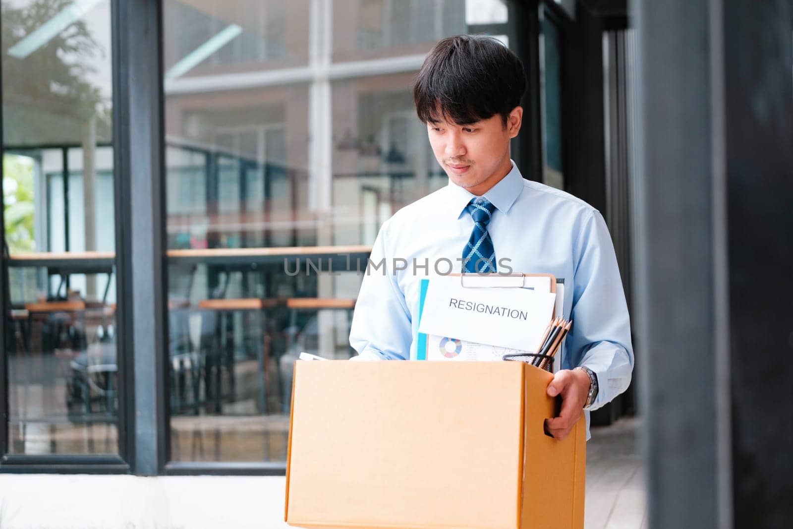 Professional Man Exiting Office with Personal Belongings and Resignation Letter, Embarking on a New Path After Job Resignation