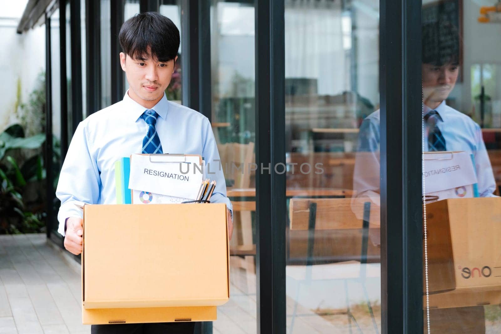 Man leaves office holding a box with personal items, including resignation letter. by ijeab