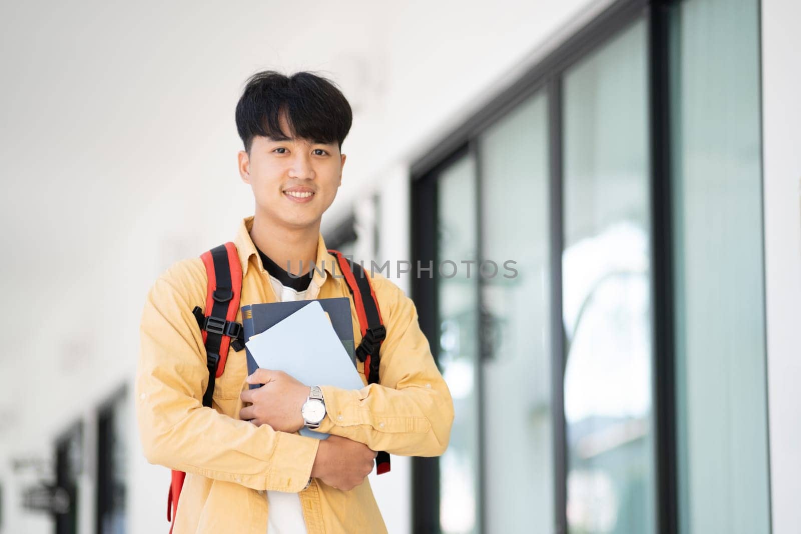 Smiling College Student Holding Books in School Corridor by ijeab