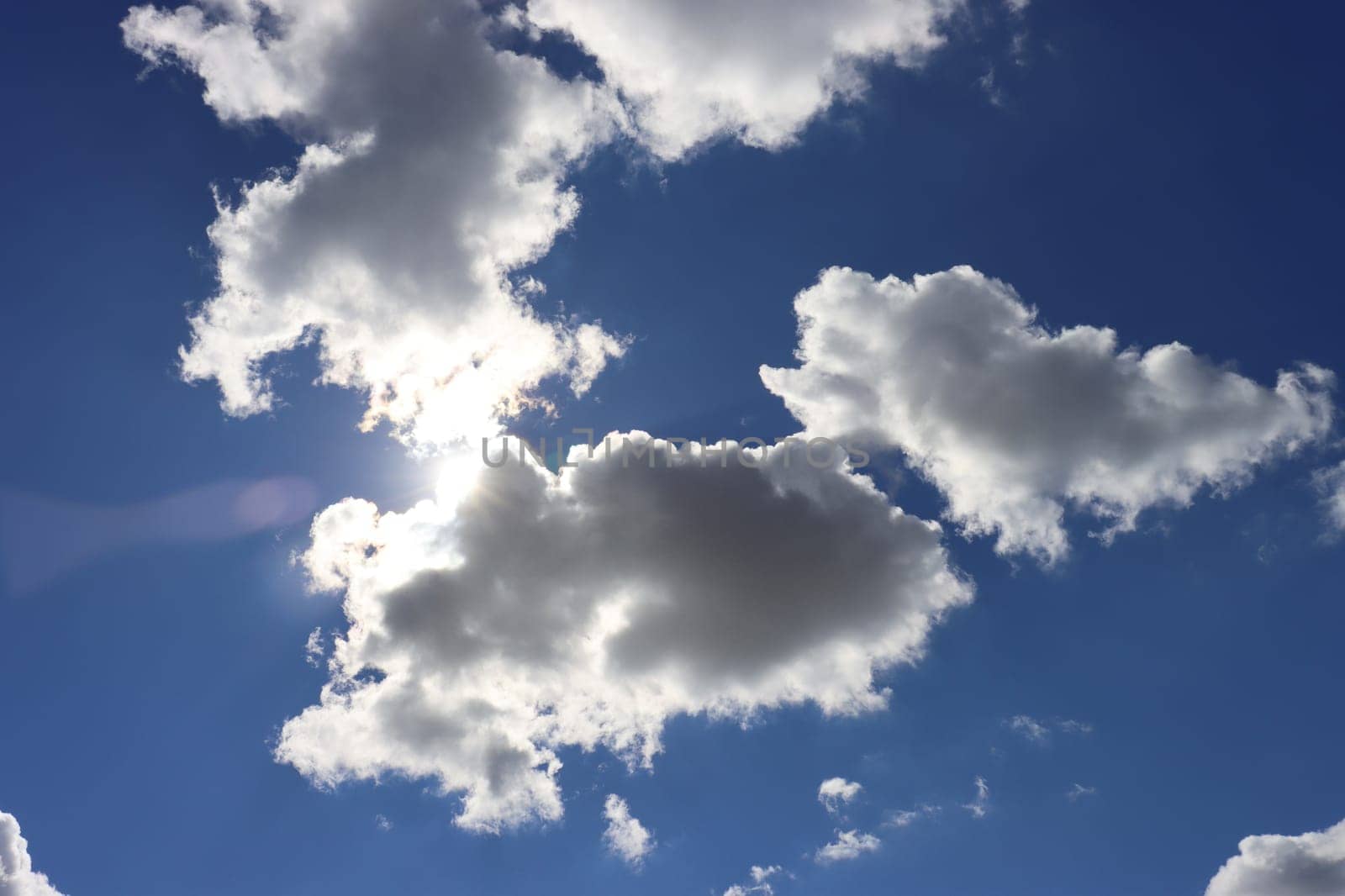 The bright sun during the day is covered by small clouds; light penetrates through the clouds.