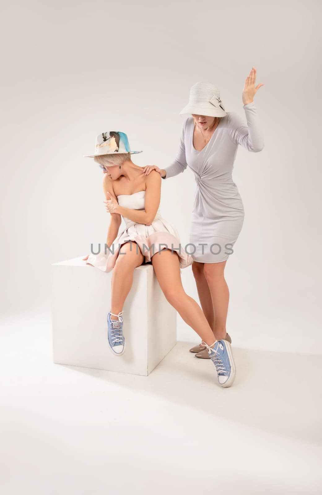 two girls in different styles of clothing playing a conflict or quarrel with each other on a white background, the psychology of human relations the conflict of the inner child and parent