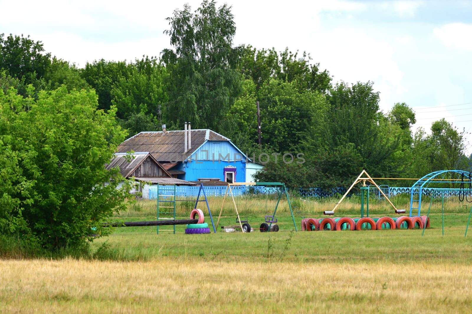 Rural house with a homemade children's playground made from tires, Russia by olgavolodina