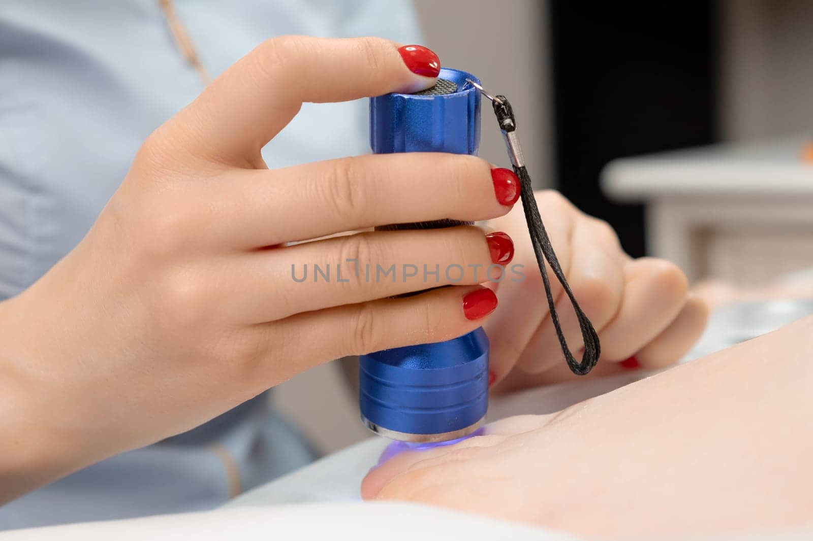 A podologist puts a titanium thread on a toenail and uses UV lamp. Chiropody concept