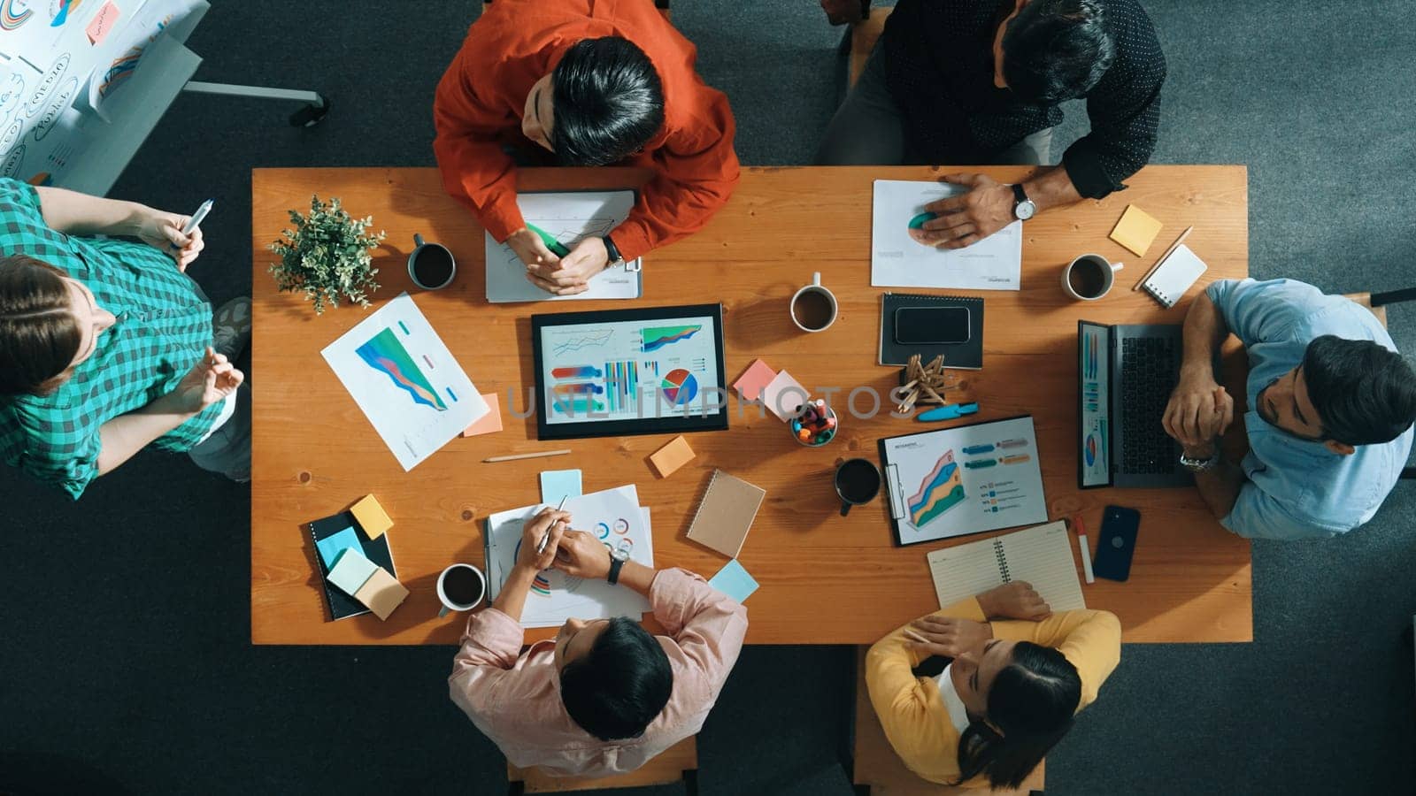 Top view of skilled business people sharing idea about startup project while standing at whiteboard. Business woman hold tablet and placed on meeting room while explain creative idea. Convocation.