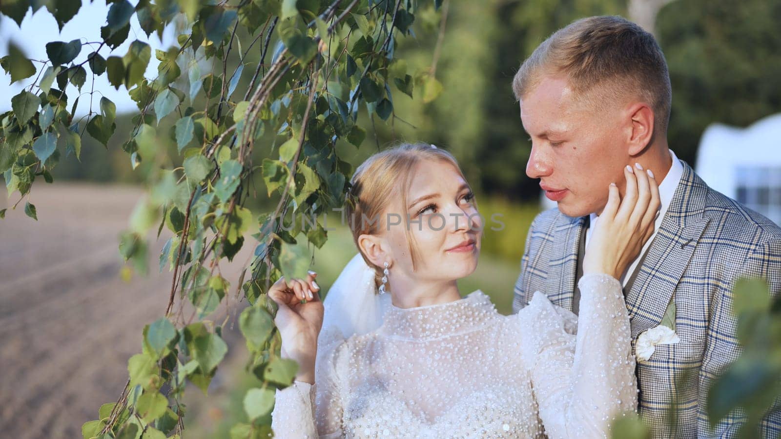 The bride and groom enjoy each other by the branches of a birch tree. by DovidPro