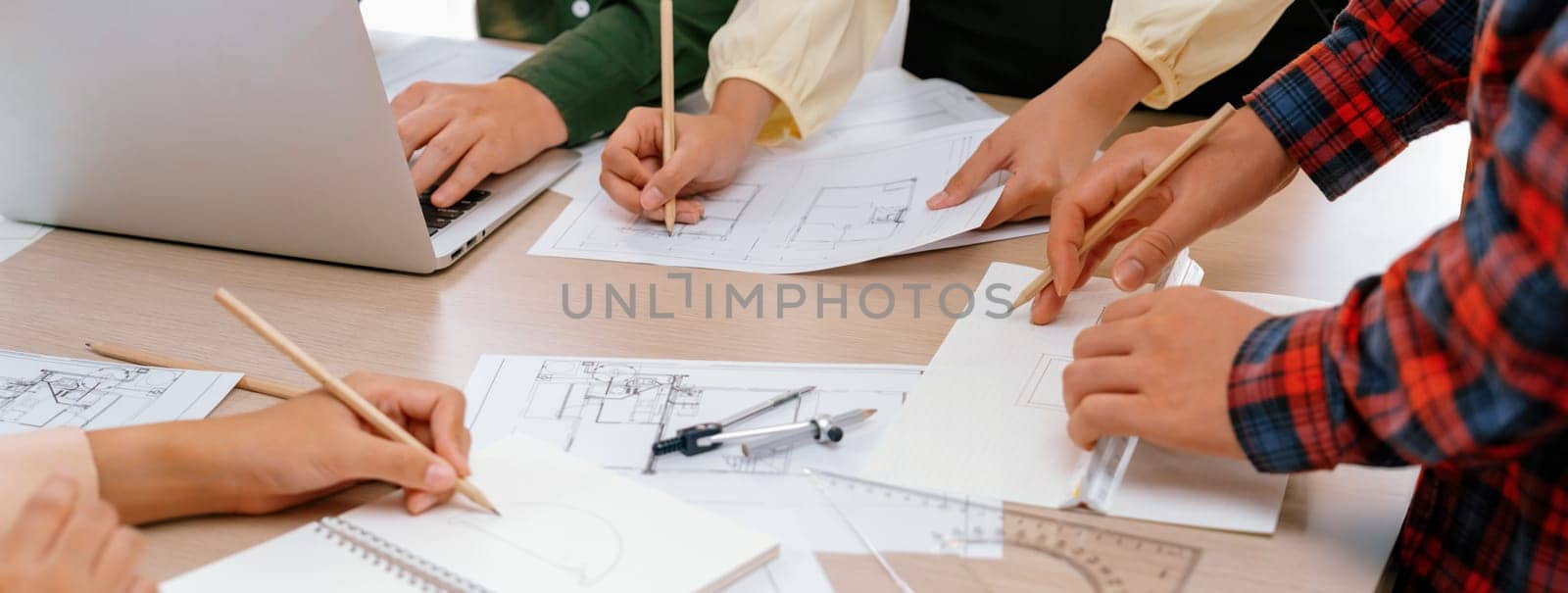 Skilled architect team using architectural equipment during colleague discussion about building design at meeting table with blueprint scatter around. Closeup. Focus on hand. Delineation.