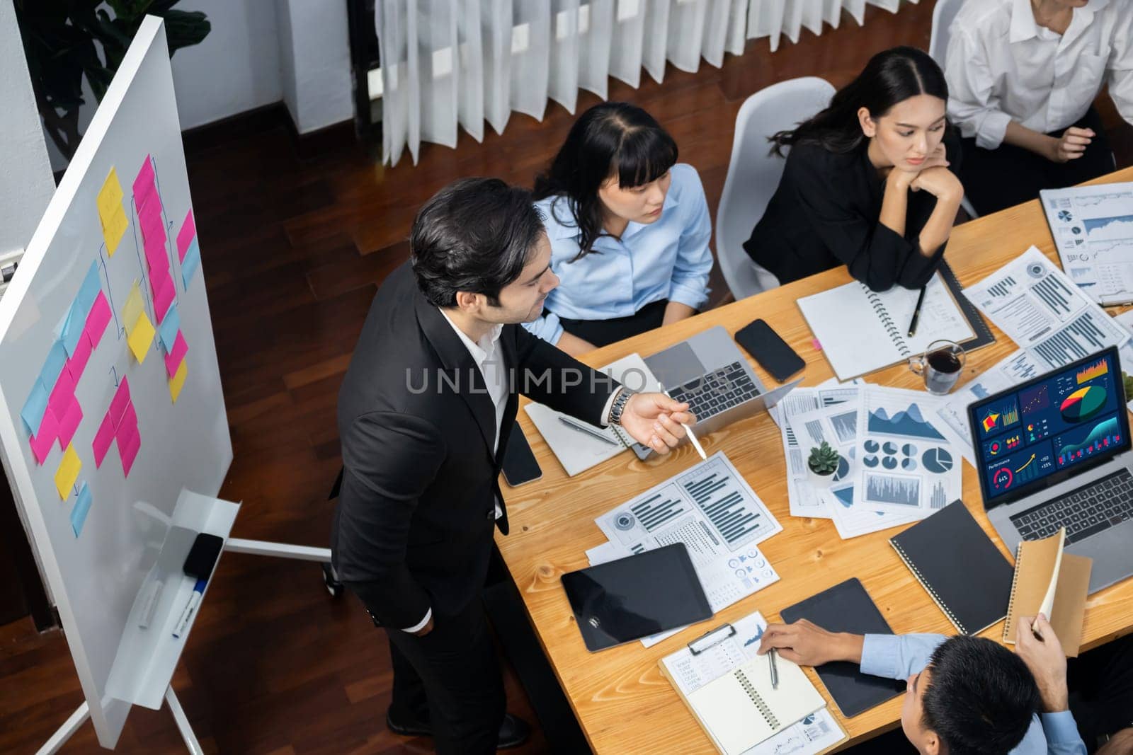 Productive boss or manager demonstrate strong commitment to effective business management on meeting room with diverse race employee, plan and discuss business marketing on meeting table. Meticulous