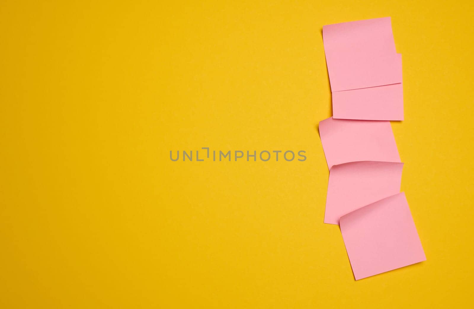 Pink square sticks are glued to the yellow background, copy space