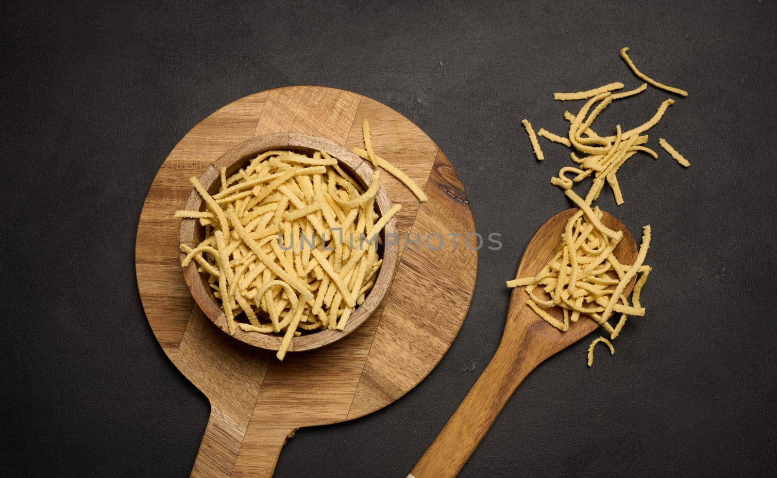 Raw wheat noodles in wooden bowl, top view by ndanko