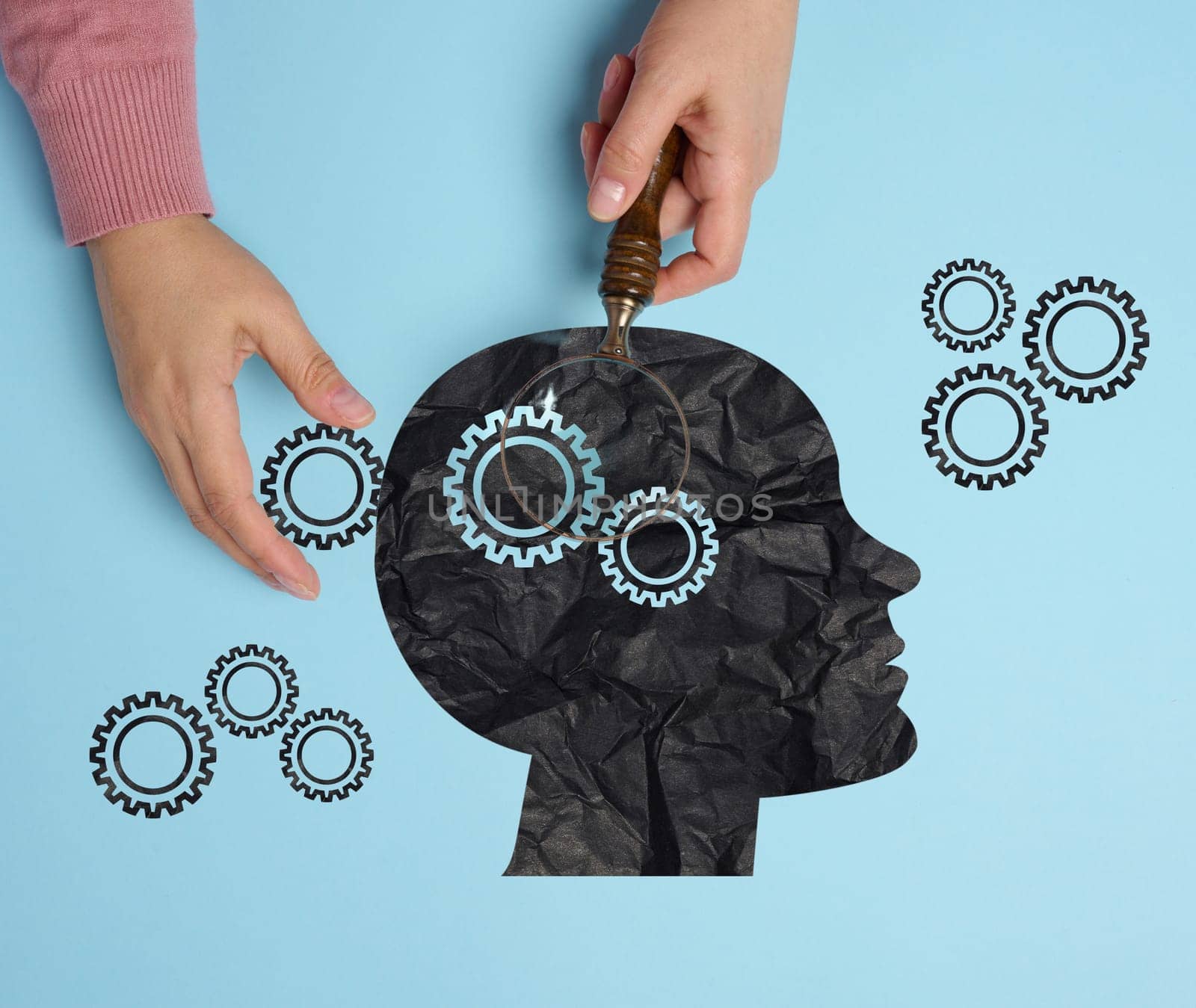 Silhouette of a human head and a woman's hand with a magnifying glass. Mental health concept, artificial intelligence training