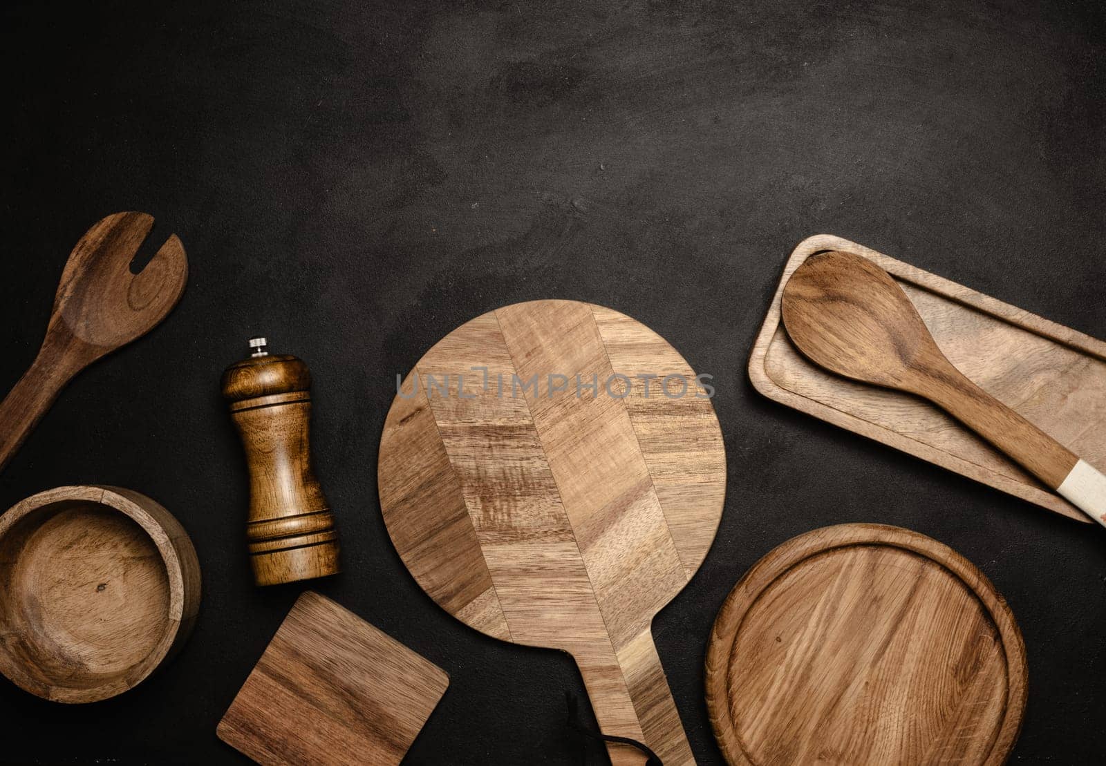 Various wooden kitchen utensils on black background, top view. Copy space