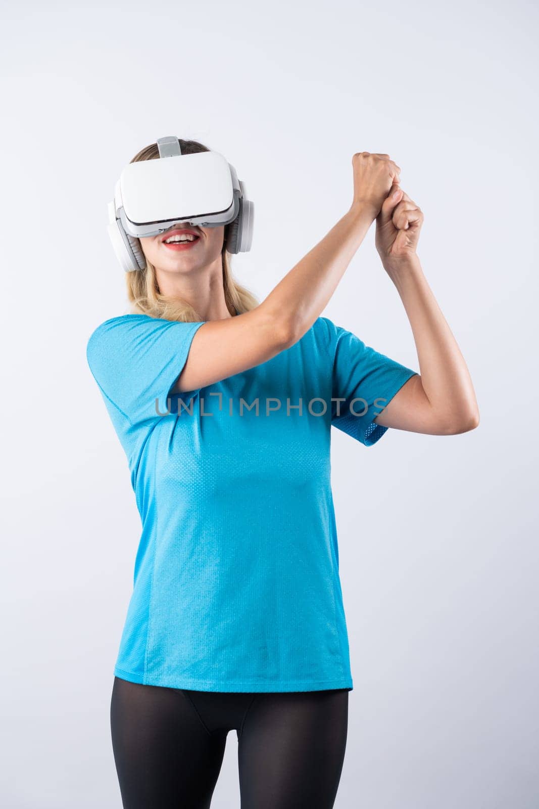 Caucasian girl playing golf and moving gesture by using VR glasses. Happy sport gamer with casual cloth playing game while wearing visual reality headset and standing at pink background. Contraption.