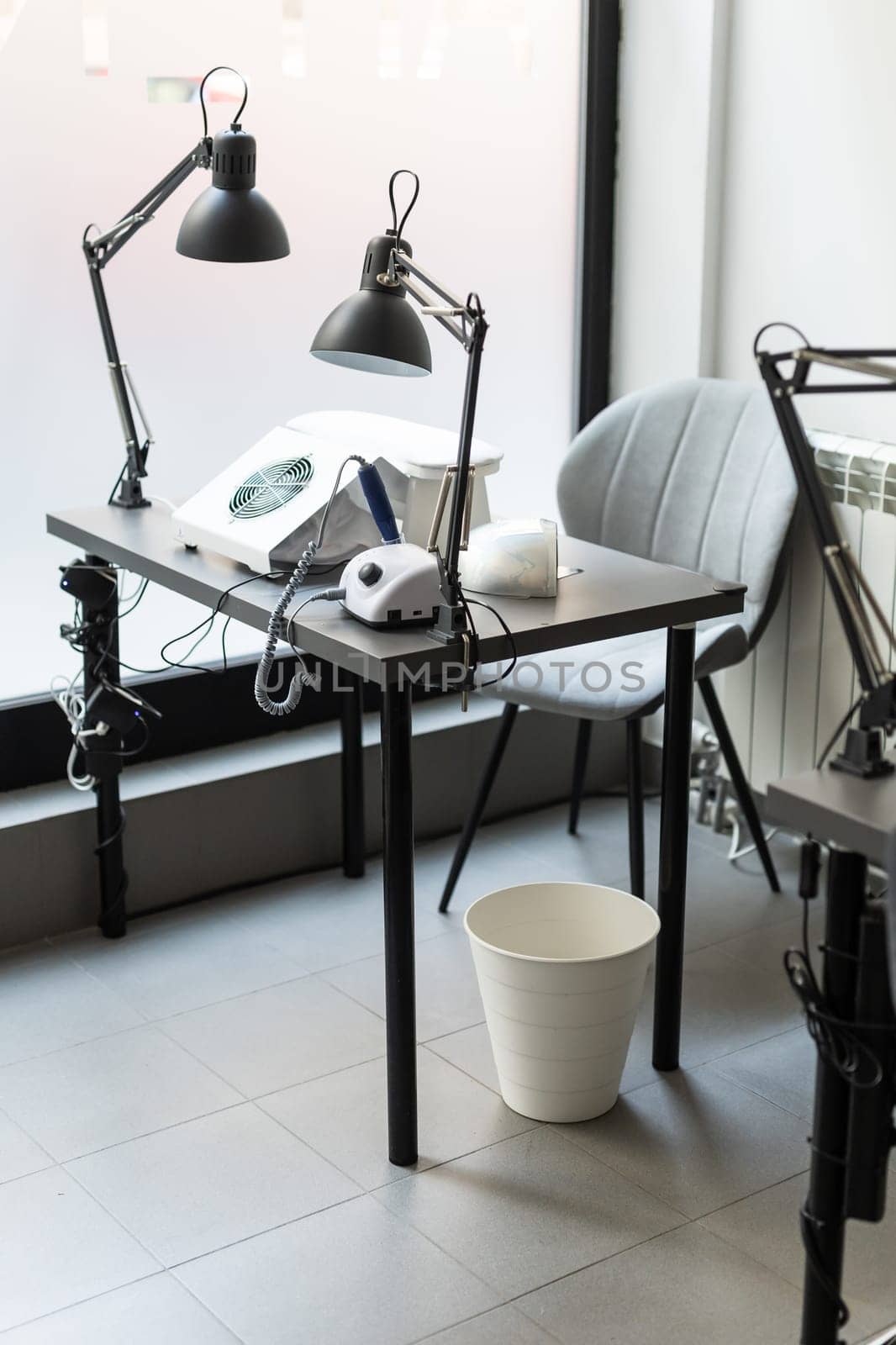Modern table with nails color palette and lamp situating in salon. Workplace for manicure. Interior