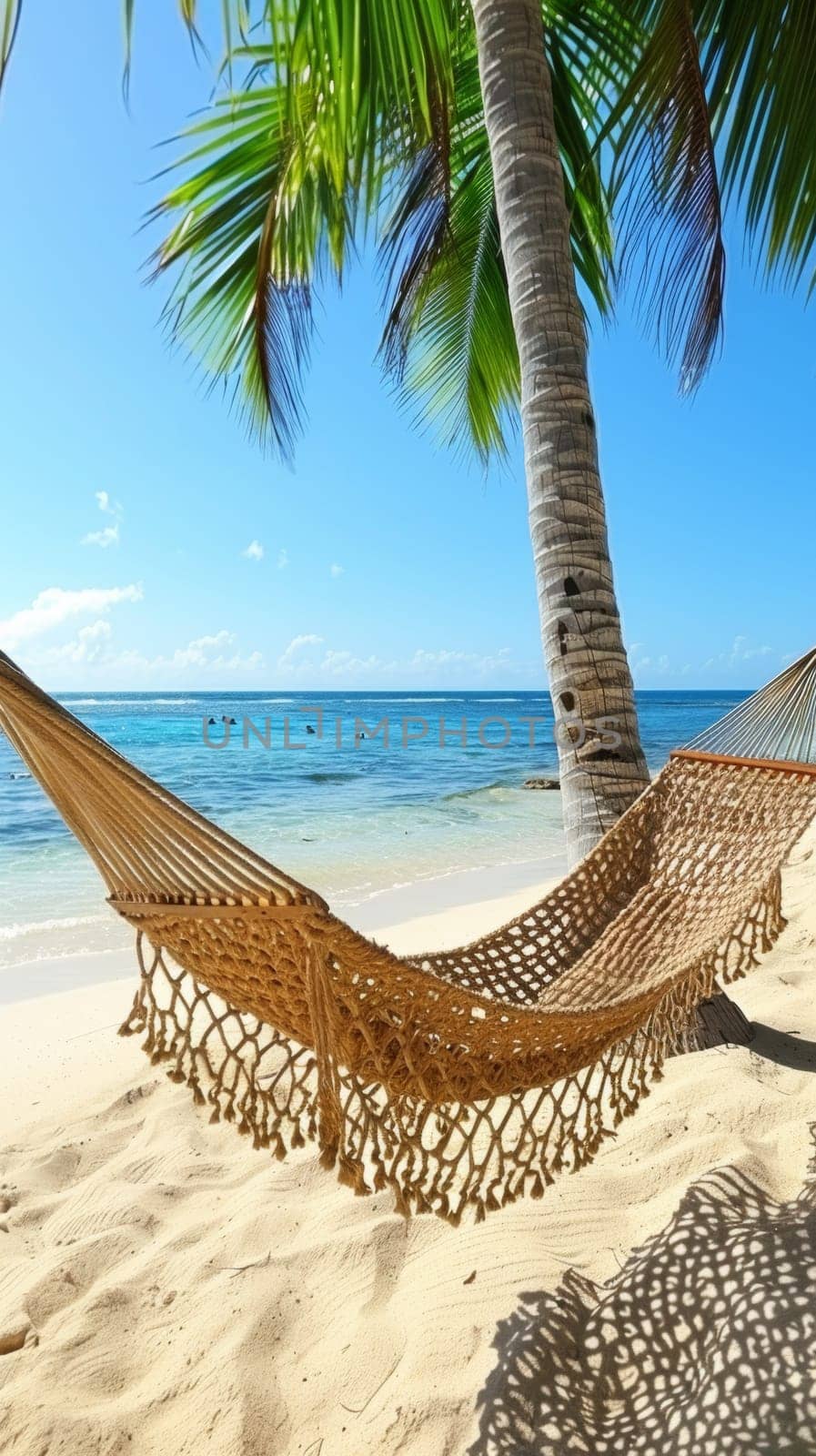 Hammock on beach under palm tree with blue sky and ocean