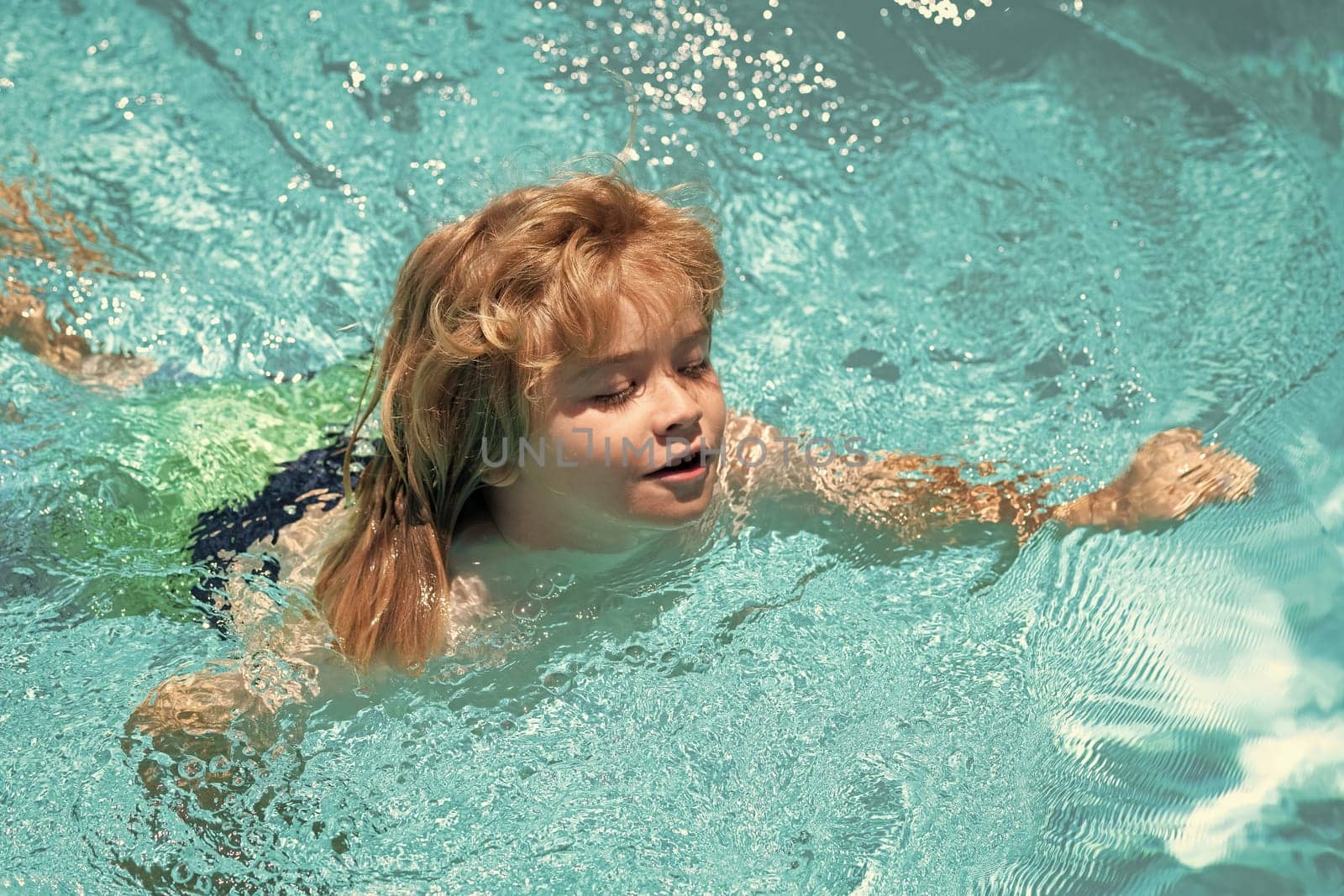 Child playing in the swimming pool. Summer kids activity. Little child playing in blue water