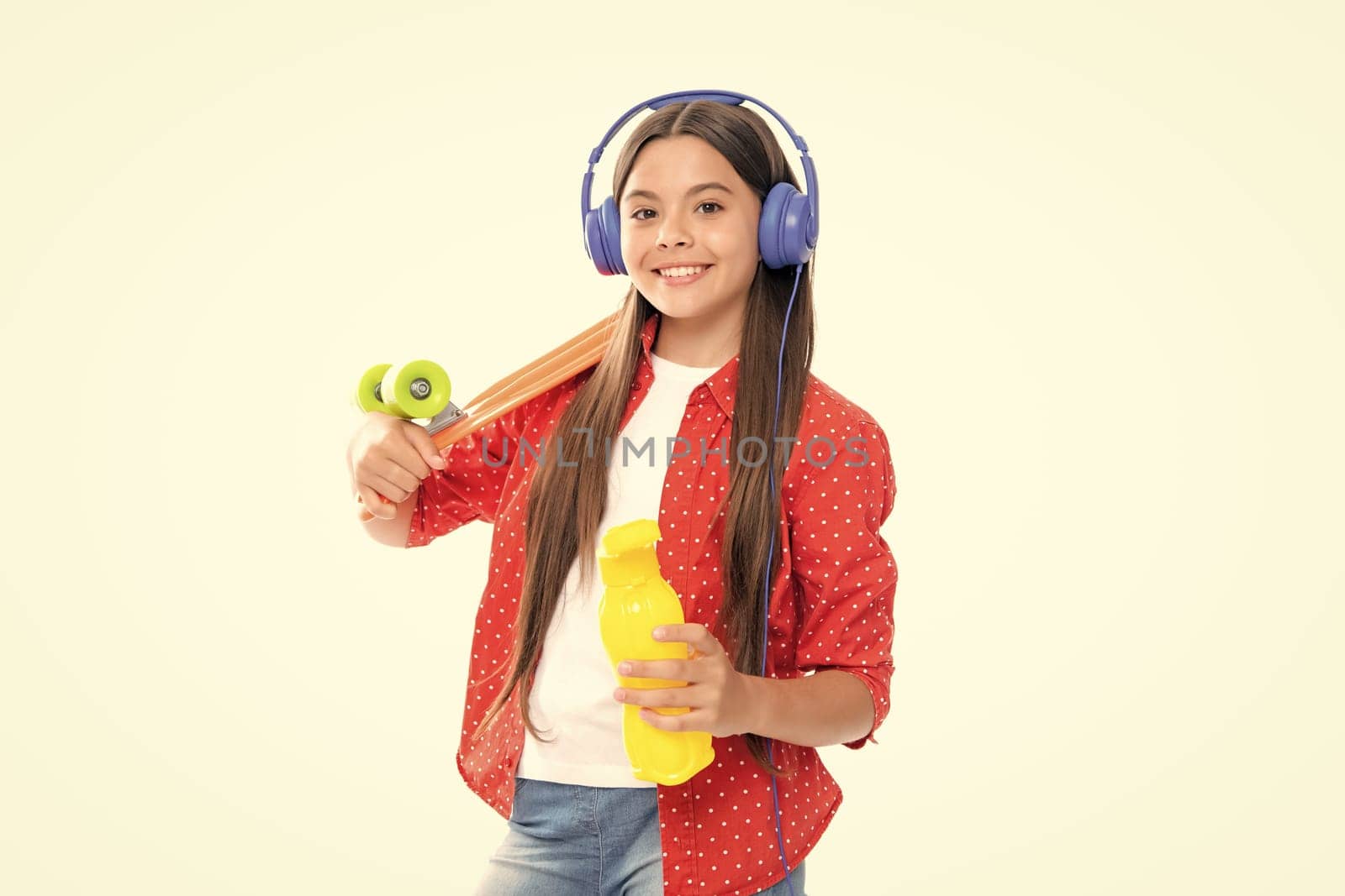 Teen girl 12, 13, 14 years old with skateboard and headphones over white studio background. Cool modern teenager in stylish clothes. Teenagers lifestyle, casual youth culture